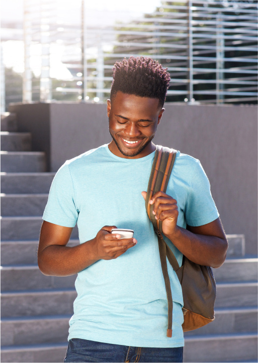 Smiling student wearing a backpack and looking at their phone.